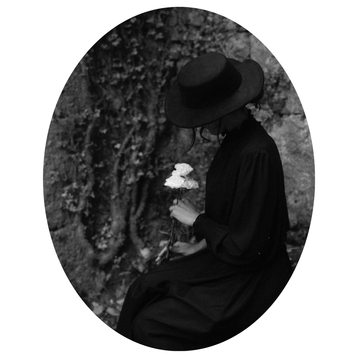 Retrato en blanco y negro de Lila Grouse sosteniendo flores blancas, símbolo del viaje interior y la esencia de La Madriguera del Tejo